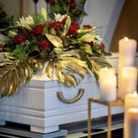 Sarggesteck mit roten Rosen und weissen Lilien und goldenen Blättern Sarggesteck mit roten Rosen und weissen Lilien individuelle Trauerfloristik